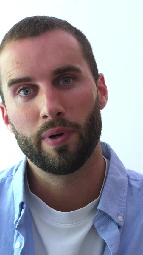 Handsome young caucasian man with a beard and blue eyes talking, waving, and Vídeos de archivo 344782117