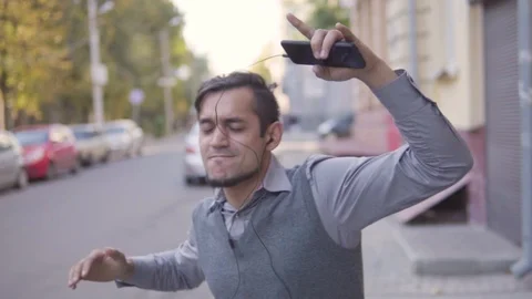 A handsome young cheerful guy is walking in the city. Running waving arms Stock Footage 113973238