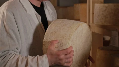 Handsome young cheese maker in uniform checking the seasoning of cheese 库存影片 180089482