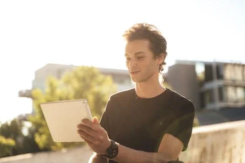 Handsome young college student using digital tablet on sunny day Stock Photos