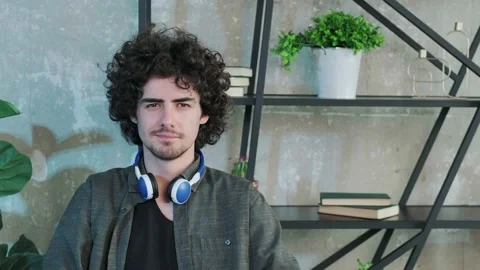 Handsome young curly haired guy looking at the camera with a happy facial Stock Footage 154903770