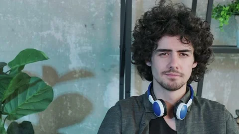 Handsome young curly haired guy looking at the camera with a happy facial Stock Footage 155240610