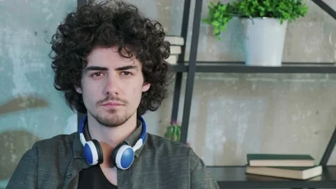 Handsome young curly haired guy looking at the camera with a happy facial Stock Footage 158450607