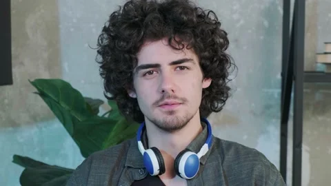 Handsome young curly haired guy looking at the camera and trying to explain Stock Footage 165341035