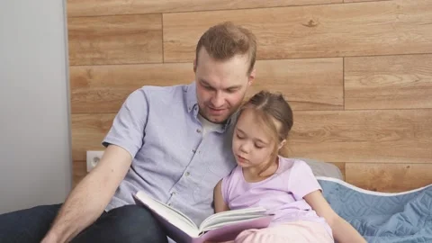 Handsome young father explaining paragraph presented in textbook to his little Stock Footage 164365498