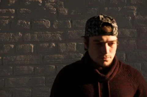 Handsome young guy in a baseball cap against brick wall background 스톡 사진