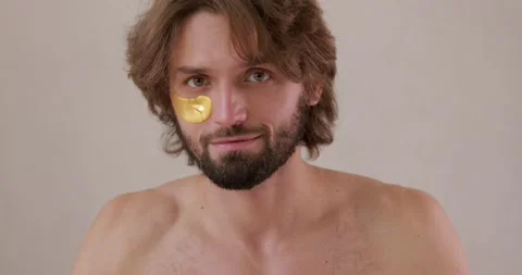 Handsome young guy with beard applying cosmetic patches under eyes. Bearded man Stock Footage 142529303
