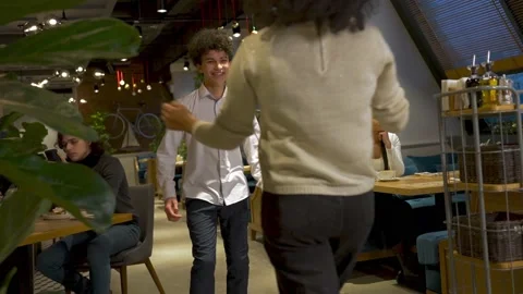 Handsome young guy hugging his girlfriend in the restaurant. Happily smiles at Stock Footage 168368487