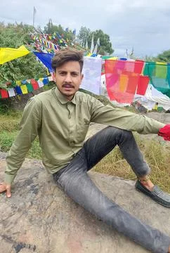 A handsome young guy looking at camera while sitting on rock with the background Stock Photos