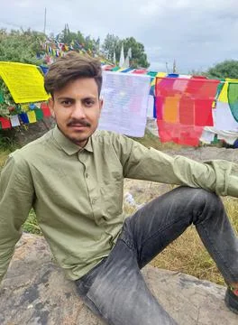 A handsome young guy looking at camera while sitting on rock with the background Stock Photos