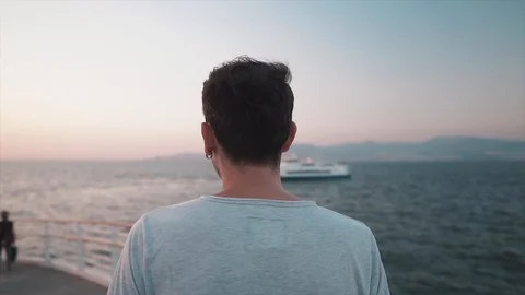 Handsome young guy is walking on pier. Following shot Stock Footage 112934691