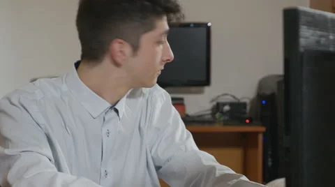 Handsome young hacker programmer coding at two computers Stock Footage 58957925