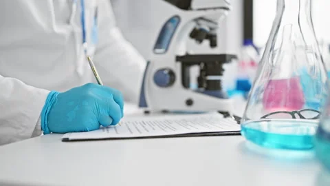 Handsome young hispanic grey-haired male scientist hulked over microscope, .. Stock Footage 261383194