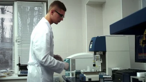 Handsome Young Laboratory Worker Putting Samples Into Automatic Testing Machine Видео 71777949