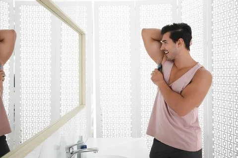 Handsome young man applying deodorant in bathroom 스톡 사진
