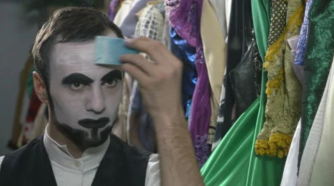 Handsome young man applying white face painting for mime make-up Stock Footage 60444837