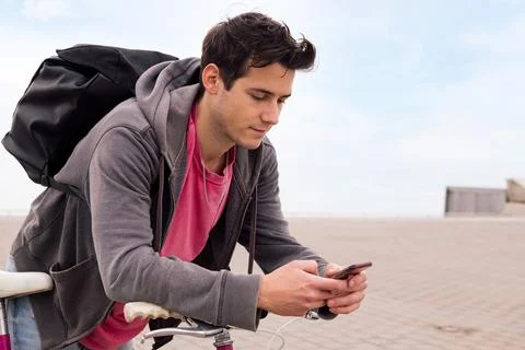 Handsome young man with backpack using smart phone Stock Photos