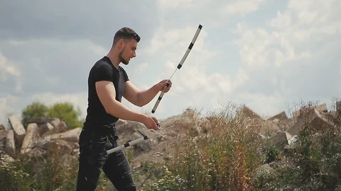 Handsome, young man with a beard in a black T-shirt demonstrates mastery with Vidéo 119470424
