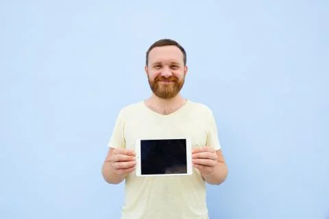 Handsome young man with a beard showing something on a tablet isolated on a b Stock Photos