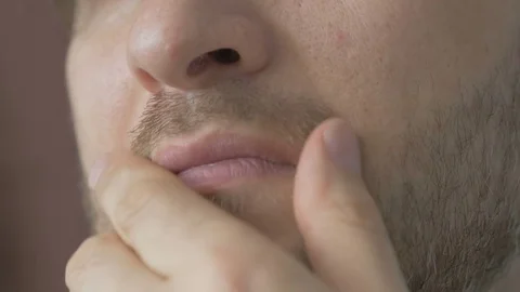 Handsome young man with a beard stroking his beard thinks Video stock 74202524