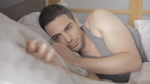 Handsome young man with a beard waking up in the morning on his bed and 스톡 동영상 110914494