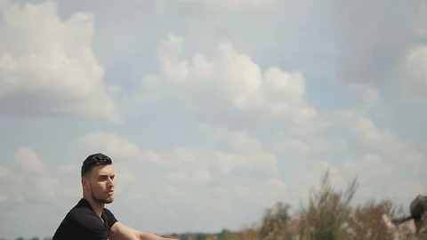 Handsome young man in black t-shirt demonstrates skill with nunchaku outdoors. 库存影片 119469799