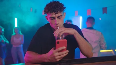 Handsome young man browsing social media on smartphone at bar counter drinking Stock Footage 115366902