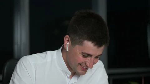 A handsome young man of Caucasian appearance works at a table and listens to Stock Footage 141062953