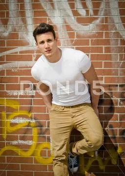 Handsome young man on city brick wall Stock Photos