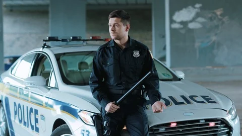 Handsome young man cops stand near patrol car look at camera around enforcement Stock Footage 113003846