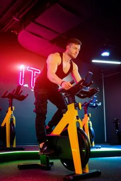 Handsome young man cycling indoor. Strong man training on bicycle trainer. Stock Photos