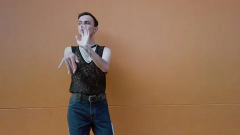 Handsome young man dancing Vogue on a coral colored wall. Hands performance Stock Footage 192077989