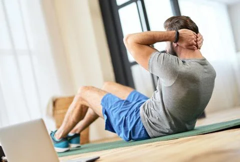 Handsome young man doing abs exercise at home Stock Photos