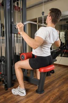 Handsome young man doing b lats pull-down workout in gym Stock Photos