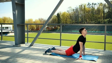Handsome Young Man Doing Hamstring Stretch Exercise On Top Of A Mat At Stadium 動画素材 108344292