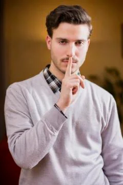 Handsome young man doing hush sign with finger on lips Stock-Fotos