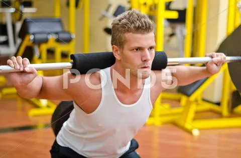 Handsome young man doing squats in gym Stock Photos