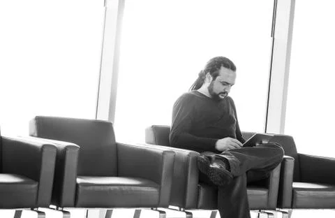Handsome young man with dreadlocks using his digital tablet pc at an airport  Stock Photos