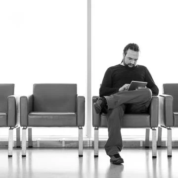 Handsome young man with dreadlocks using his digital tablet pc at an airport  Stock Photos