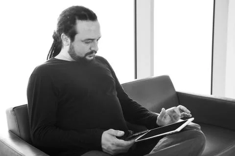 Handsome young man with dreadlocks using his digital tablet pc at an airport  Stock Photos
