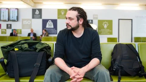 Handsome young man with dreadlocks waiting at an airport lounge. Stock Photos
