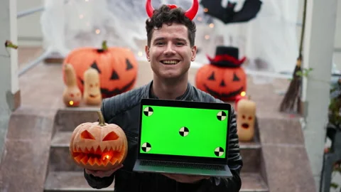 Handsome Young man dressed as a vampire devil with makeup holds a pumpkin Jack O Stock Footage 219814152