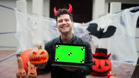 Handsome Young man dressed as a vampire devil with makeup holds a pumpkin Jack O Stock Footage 219856252