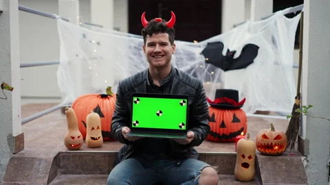 Handsome Young man dressed as a vampire devil with makeup holds a pumpkin Jack O Stock Footage 251747999