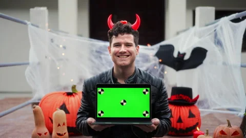 Handsome Young man dressed as a vampire devil with makeup holds a pumpkin Jack O Stock Footage 251748179