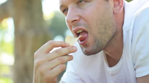 Handsome young man eating chips outdoors Stock Footage 6530499