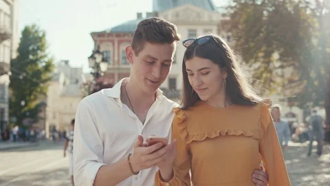 Handsome young man embracing waist of his cheerful attractive young girlfriend Stock Footage 91992453