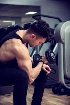 Handsome young man exercising biceps in gym Stock Photos