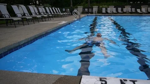 Handsome young man floating relaxing on water in a swimming pool Stock Footage 73451852