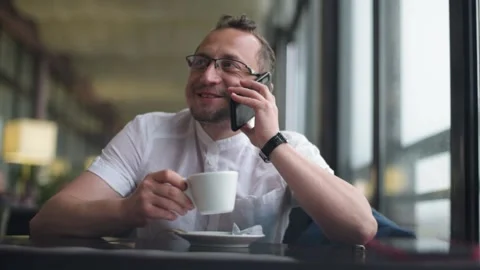 Handsome young man having coffee and using a smartphone at a cafe. Stock Footage 156189539